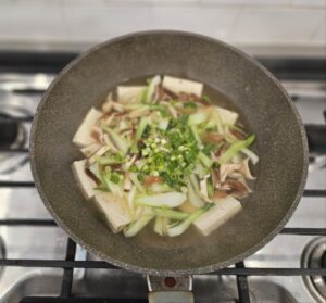 green onions on top of bok choy and tofu soup