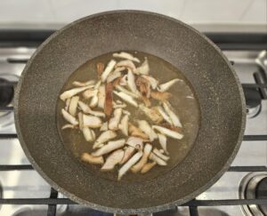 Mushrooms and broth in a pot over a stove