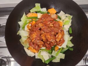 Spicy chicken on top of vegetables in a wok pan