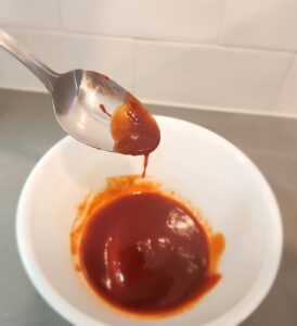 Honey gochujang drizzle in a bowl with spoon