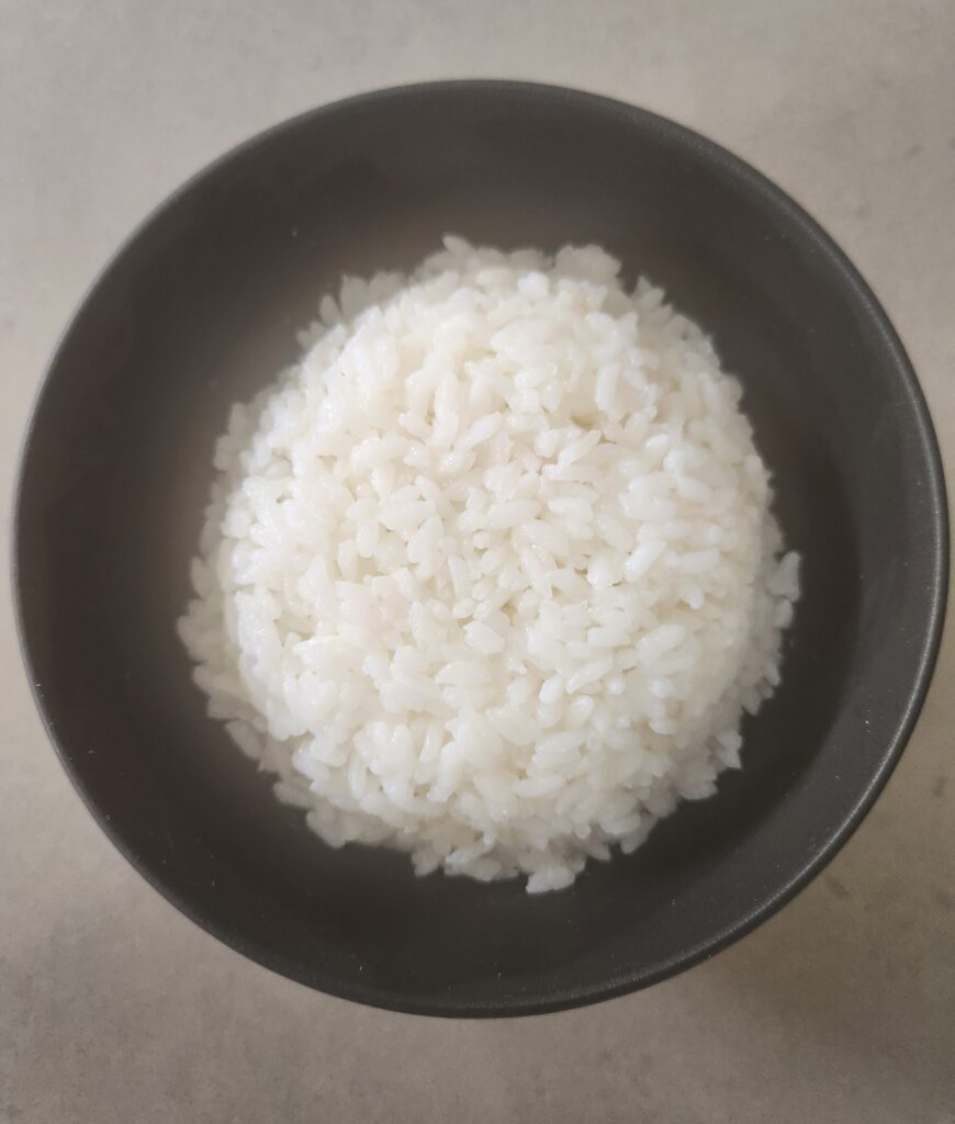 Picture of white rice in a black rice bowl.